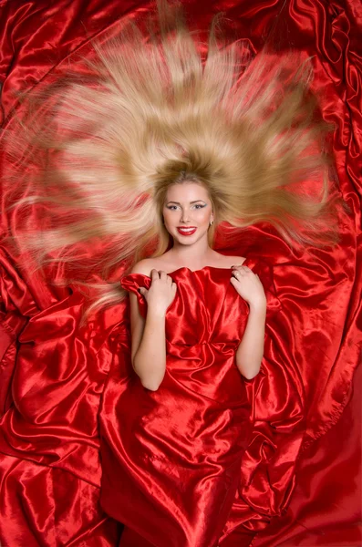 Blonde with long hair on red fabric — Stock Photo, Image