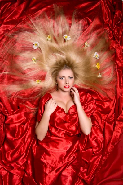 Blondynka z długimi włosami na czerwone tkaniny — Zdjęcie stockowe