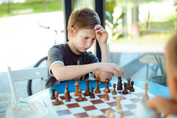 мальчик играет в шахматы в зеленом летнем парке