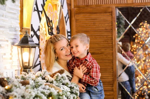 クリスマスの装飾が施された部屋で母親は息子の腕を抱いたり抱っこしたりくすぐったりして笑っています — ストック写真