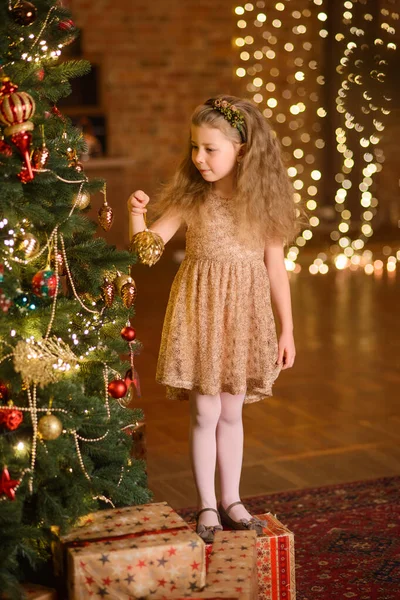 드레스를 소녀가 크리스마스 근처에 있습니다 화랑에서 나오는 불빛을 배경으로 장난감을 — 스톡 사진