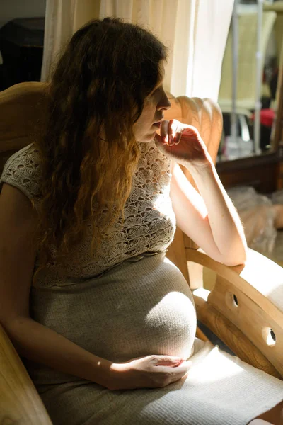 一个孕妇坐在一张椅子上 在清晨的阳光下 在一个房间里 — 图库照片