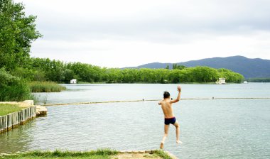 Child jumping to Bañolas's lake clipart