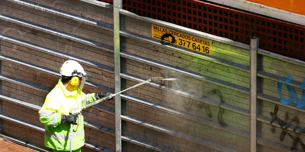 Hombre limpiando graffiti en una cerca — Foto de Stock