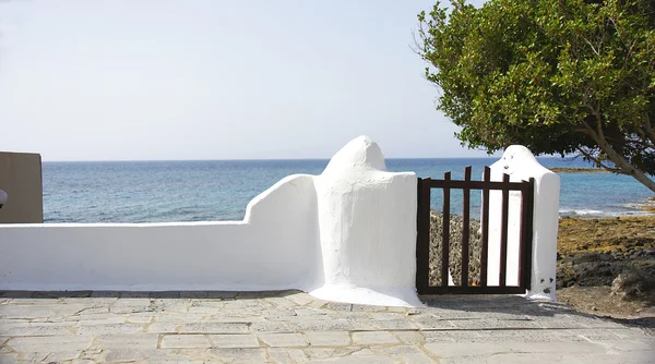 Vit vägg med staket och havet i bakgrunden i costa teguise — Stockfoto