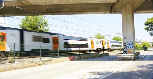 Personenzug fährt unter einer Brücke durch — Stockfoto