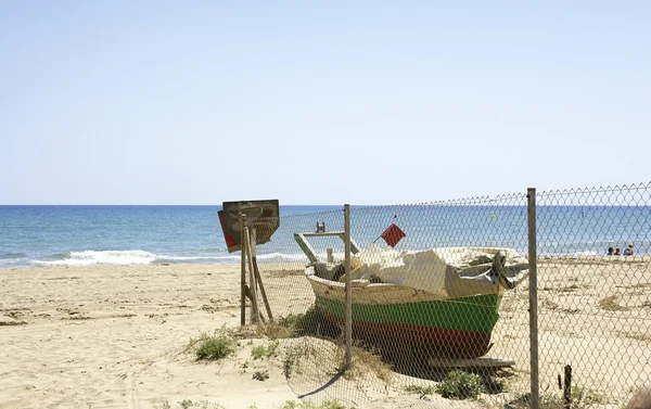 Viejo muelle de madera oxidado en la costa arenosa — Foto de stock