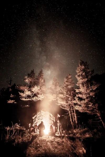 Turistas cerca de un fuego bajo las estrellas — Foto de Stock