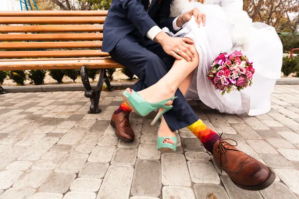 Gelin ve damat bankta parlak giysiler içinde.
