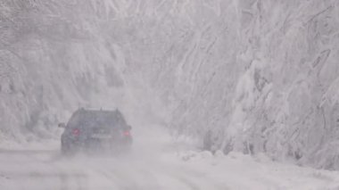 Ağır çekim. Tehlikeli bir yol. Kar fırtınası. Araba karlı bir yolda ilerliyor.