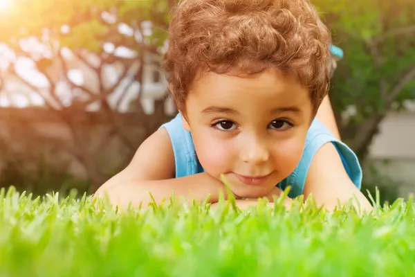 Дитячий хлопчик лежить на зеленому полі — стокове фото