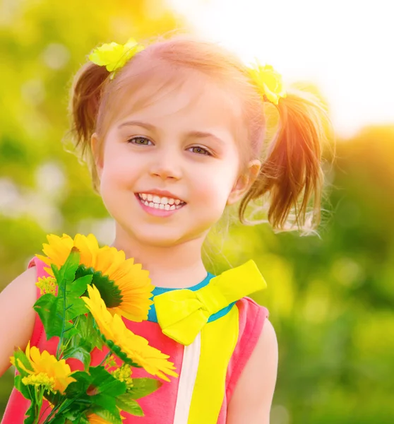 Glückliches kleines Mädchen mit Sonnenblumen — Stockfoto