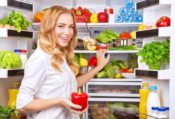 Dona de casa tomar pimenta vermelha da geladeira — Fotografia de Stock