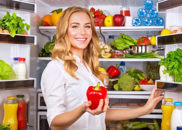 Hemmafru på köket ta röd paprika från kylskåp — Stockfoto