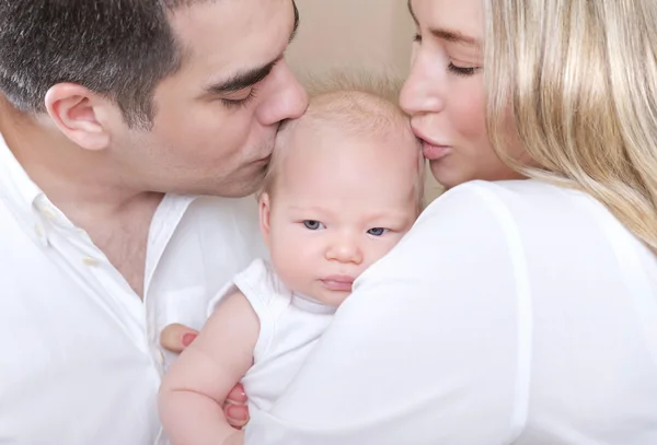 Young parents kissing baby — Stock Photo, Image