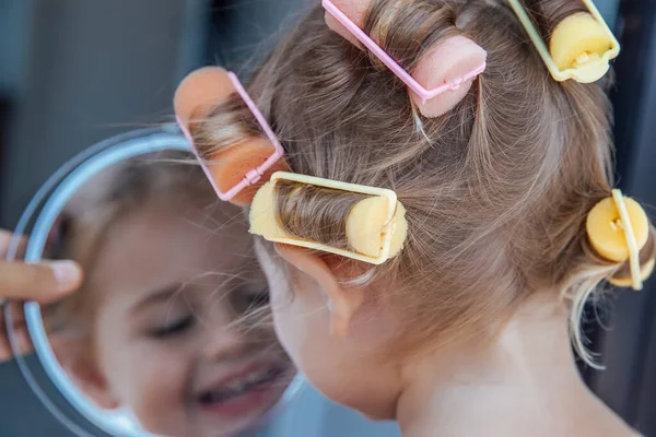 一个漂亮的小女孩的画像 她的头发上有五彩缤纷的卷发 享受着镜中的倒影 快乐的Childs乐趣 活跃的童年 — 图库照片