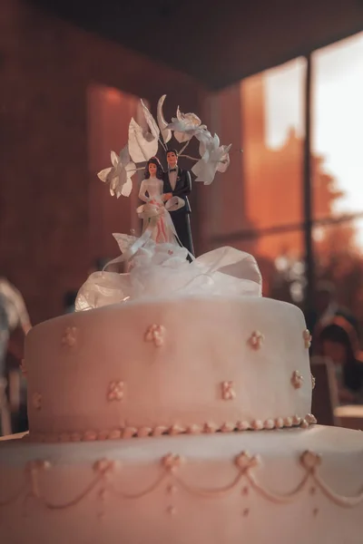 Photo of a Tasty Wedding Cake with Traditional Wedding Toys on the Top. Bride and Groom Dolls. Festive Dinner in Restaurant. New Family Concept.