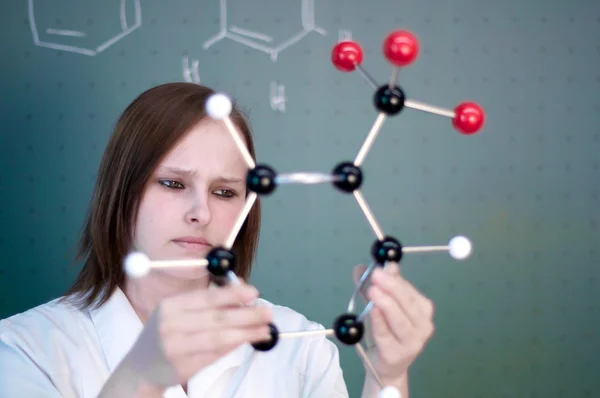 Female college student looking into a chemical model — Stock Photo, Image