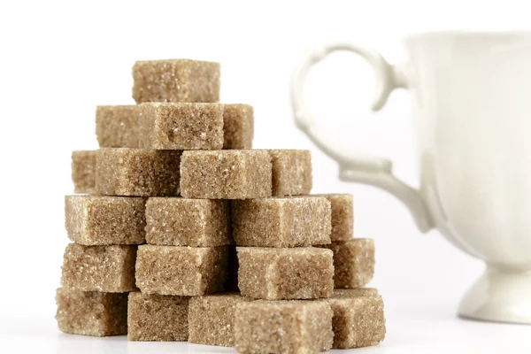 Brown sugar cubes and a cup — Stock Photo, Image
