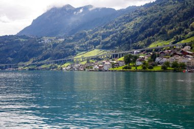 Lucerne Gölü 'nün kıyısındaki tepenin yamacındaki konut binaları uzaktan görülebilir. Dört Kantonun Gölü.
