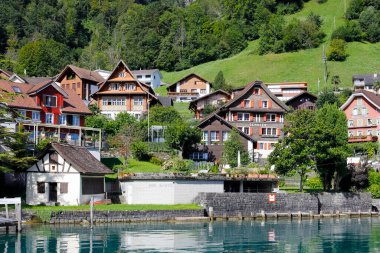 Bauen, İsviçre - 25 Ağustos 2020: Lucerne Gölü kıyısındaki küçük bir kasabadaki evler. Arka planda orman yamacı var..