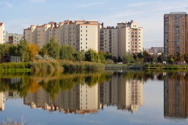 Varşova, Polonya - 11 Ekim 2021: Birçok ailenin yaşadığı apartman dairesi, yansımalarının görülebildiği göl kıyısında yer almaktadır..
