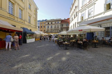 Lublin, Polonya - 10 Eylül 2021: Asfalt kaldırımda, eski kasaba evlerinin yanında güneşli bir günde burada görülebilen açık hava restoranları ve tezgahlar var..