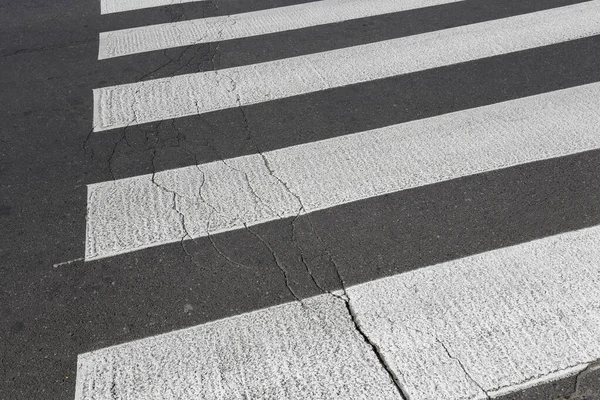 黒いアスファルトの上の白い縞模様は横断歩道です — ストック写真