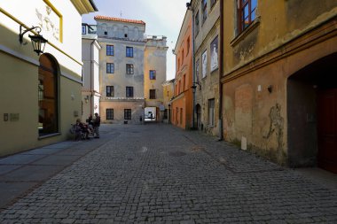 Lublin, Polonya - 11 Eylül 2021: Asfalt sokaktaki eski apartman evleri şehrin eski kesiminde yer almaktadır. Şu anda bu binaların yakınında sadece birkaç kişi var, ama araç yok.