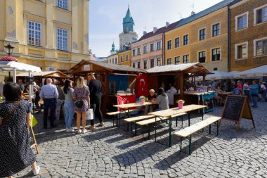 Lublin, Polonya - 11 Eylül 2021: İnsanlar yemek pişirme etkinliği sırasında eski kasaba meydanında görüldüğü gibi çeşitli mutfakların sunulduğu tezgahlarda toplanıyorlar.