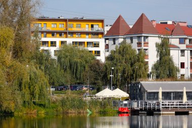 Varşova, Polonya - 11 Ekim 2021: Goclaw konut bölgesi ve bir göl. Gölün kıyılarında bir kafeye ev sahipliği yapan küçük binası olan çeşitli mimari yapılar vardır..