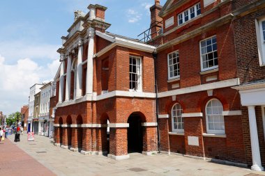 Chichester, İngiltere, İngiltere - Haziran 06, 2010: Şehrin sokaklarından birinde kırmızı tuğladan yapılmış büyük bir bina bulunmaktadır. Biraz uzakta insanların bu sahnede yürüdüğünü görebilirsiniz.