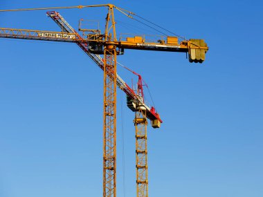 Varşova, Polonya - 21 Aralık 2021: Goclaw konutlarındaki inşaat alanında çalışan iki vinç. Orada turna kuşları görünür, güneşli mavi gökyüzüne karşı.