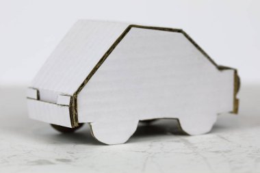 Beyaz kartondan yapılmış bir araba modeli. Geri dönüşümlü ambalaj malzemesi bu araba modelini elde yapmak için kullanıldı.