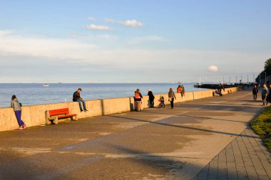 Gdynia, Polonya - 25 Mayıs 2022: Beton bir dalgalanma ile Gdansk Körfezi 'nden ayrılmış geniş bir gezinti alanı. Boş zamanlarını onunla geçirmekten hoşlanan insanlar var.