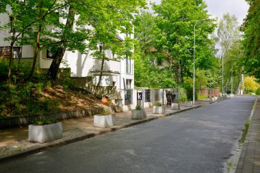 Gdynia, Polonya - 26 Mayıs 2022: Bir yerleşim bölgesinden geçen caddede araba trafiği yok. Burada bir sürü bitki ve ağaç var.