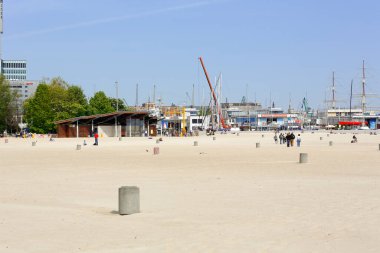 Gdynia, Polonya - 24 Mayıs 2022: Serin Mayıs gününe rağmen yaz mevsiminden önce bile boş zamanlarını burada geçirmeyi seven az sayıda insanla dolu kumlu bir şehir plajı