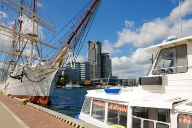 Gdynia, Poland - May 27, 2022: Dar Pomorza, a three-masted training sailing ship, now a museum ship and another ship at the quay. Modern buildings are seen a little further