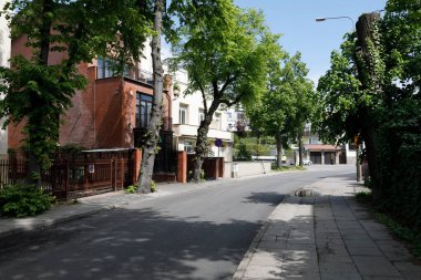 Gdynia, Polonya - 30 Mayıs 2022: Bir yerleşim bölgesindeki Dar Sokak. Güneşli bir bahar gününde gölgeli ağaçlar vardır..