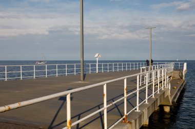 Gdynia, Polonya - 25 Mayıs 2022: Gdansk Körfezi 'nin sularında küçük bir beton iskele var. Rıhtımda balık tutan biri var.