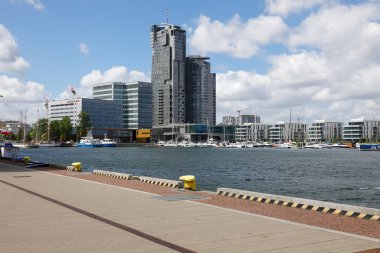 Gdynia, Poland - May 27, 2022: A bit further there are modern buildings that can be seen beyond the waters of the Gulf of Gdansk, in the Gdynia port.