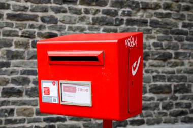 Bruges, Belçika - 13 Eylül 2022: Kırmızı posta kutusu tuğla bir duvara karşı bir direğe monte edilmiştir ve vatandaşların ve turistlerin onlara kartpostal veya mektup göndermelerine izin vermeleri için büyük bir yardımdır.