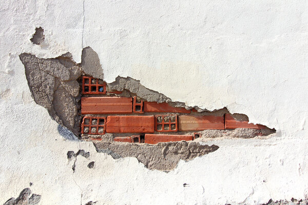 Белая стена со сломанными кирпичами и обломками под наблюдением
