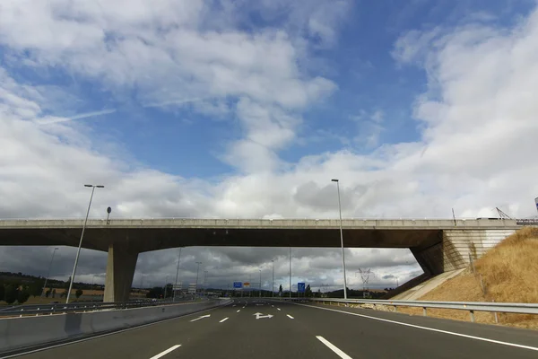 Carretera con puente que cruza la carretera y el cielo azul con cl blanco —  Fotos de Stock