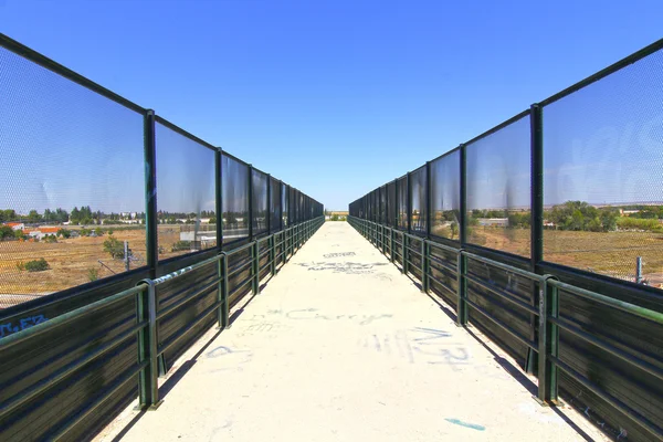 Перспектива в проходе моста с заборами — стоковое фото