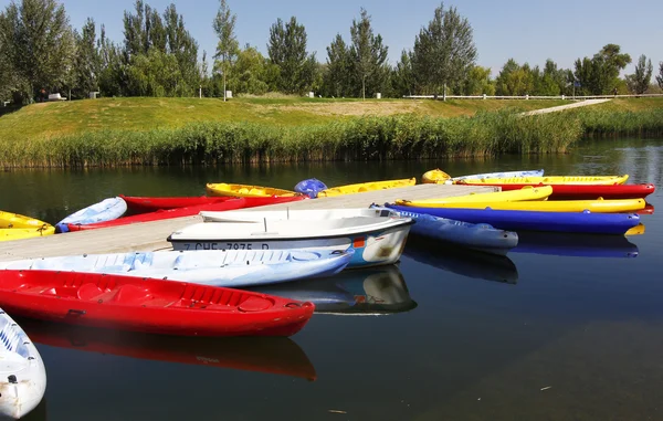 Barcos y canoas hechas de muchos colores en un lago tranquilo con s azul — Foto de Stock