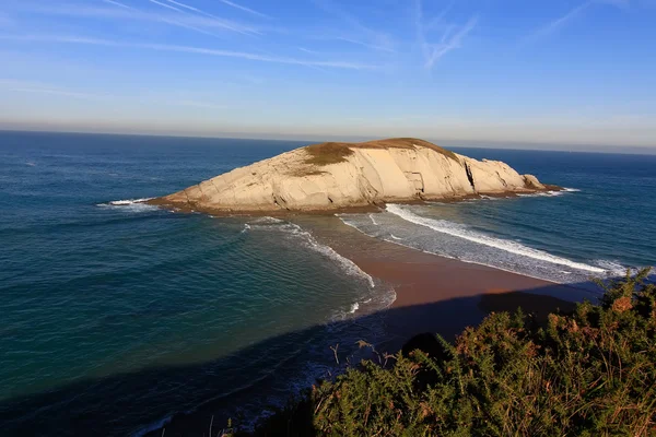 Île reliée par une flèche de sable à la côte, avec des vagues sur deux — Photo