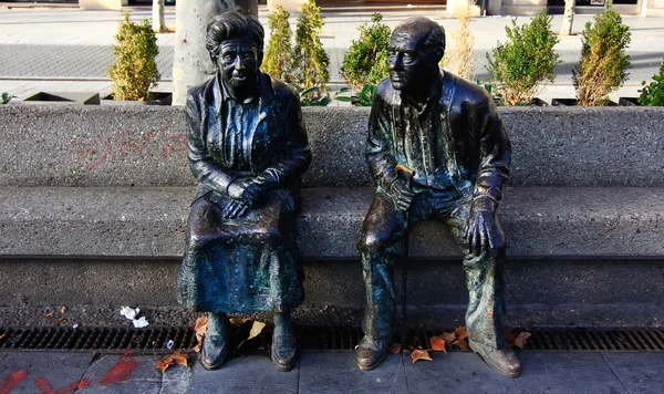 Figurines en bronze couple âgé assis dans le parc — Photo