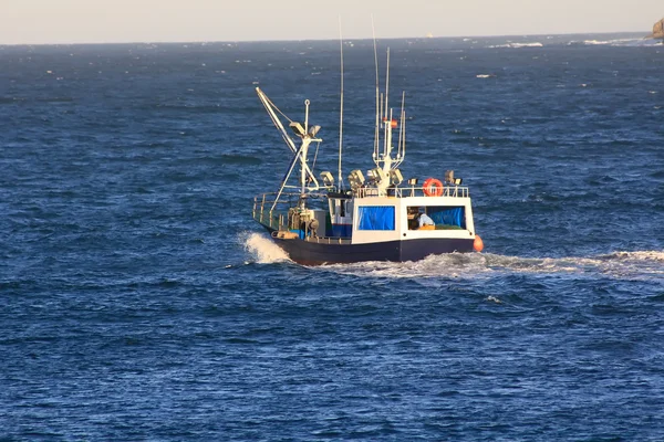 Small fishing boat sailing near the coast in a blue sea — Stock Photo, Image