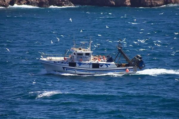 Small fishing boat sailing near the coast in a blue sea — Stock Photo, Image